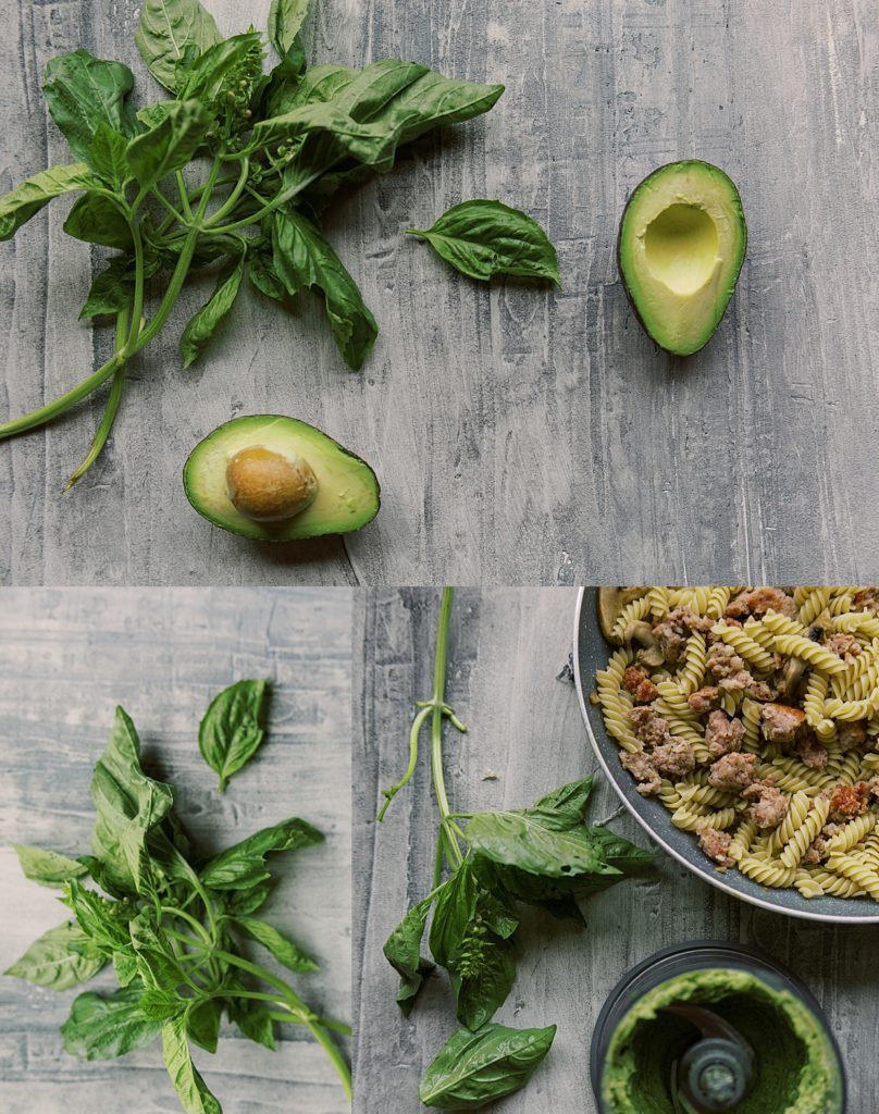 Avocados and basil made into a creamy avocado pesto sauce served with rotini pasta, sausage, and mushrooms in a skillet on a cement countertop. 